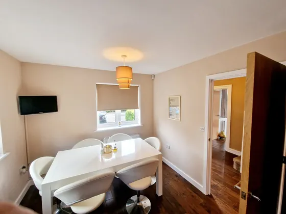 Dining room with pale walls, a white table and a dark wood door