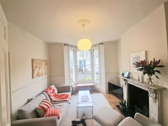 Living room with white walls, a fireplace and a bay window