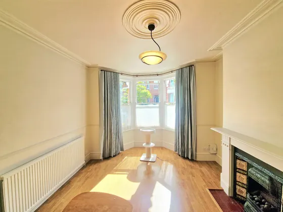 Living room with a bay window, cream walls and a cast iron fireplace