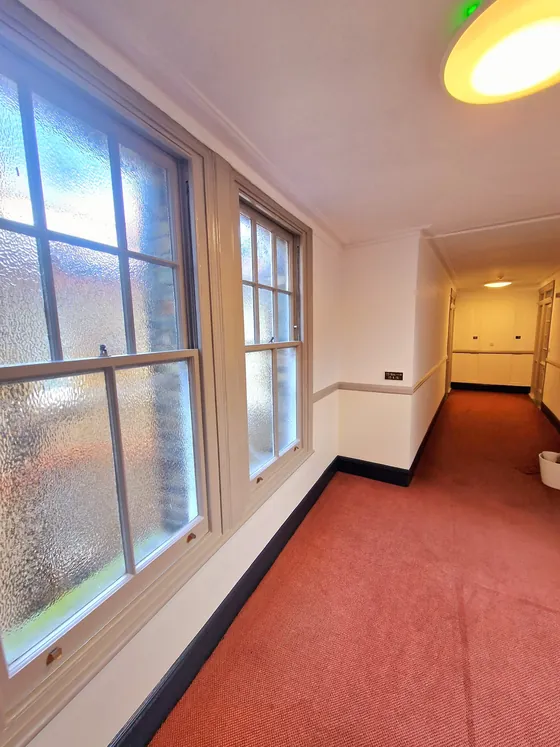 Corridor with sash windows, cream walls and a red carpet