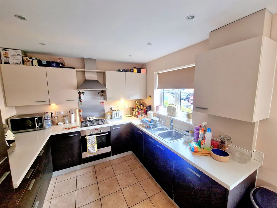 A kitchen with cream wall units, dark base units and a tiled floor